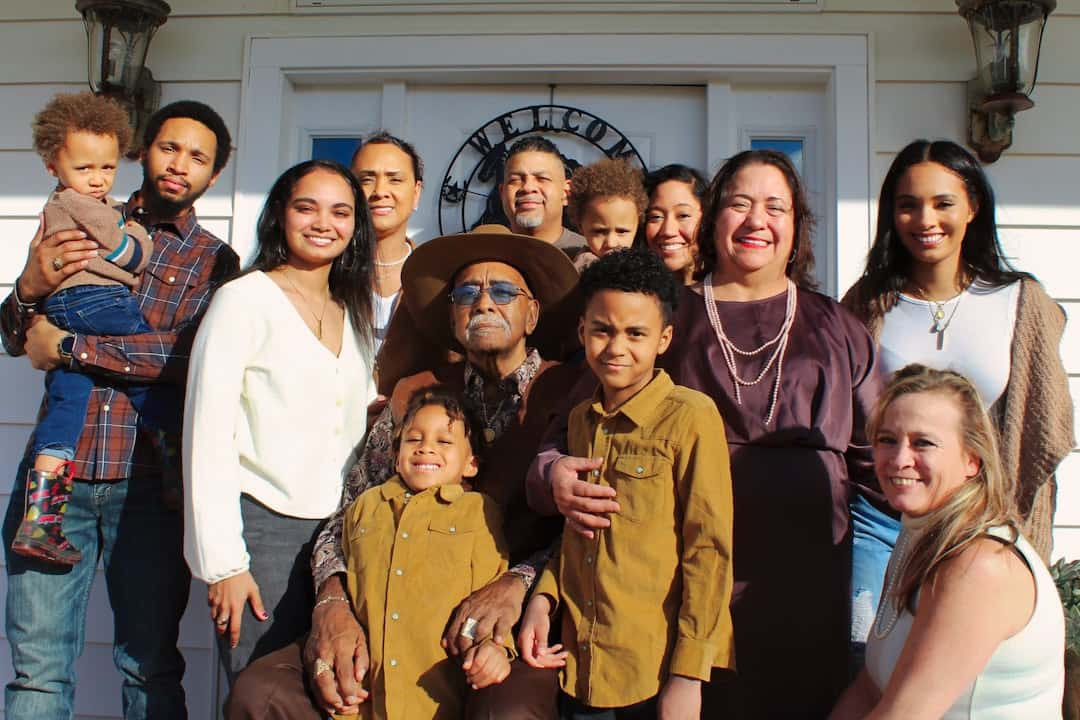 Multi-generational Latino family gathered in a kitchen with warm light