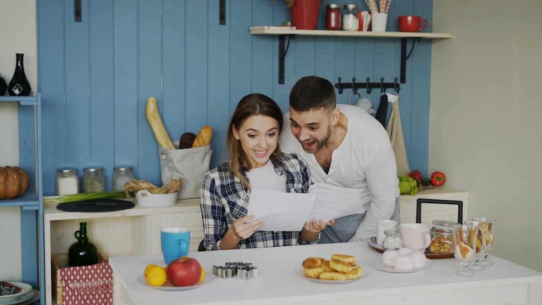 Pareja revisando papeles en una cocina moderna iluminada por el sol