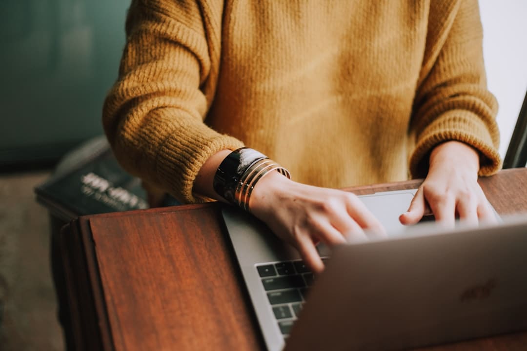 Hands typing on a laptop next to organized documents in warm light